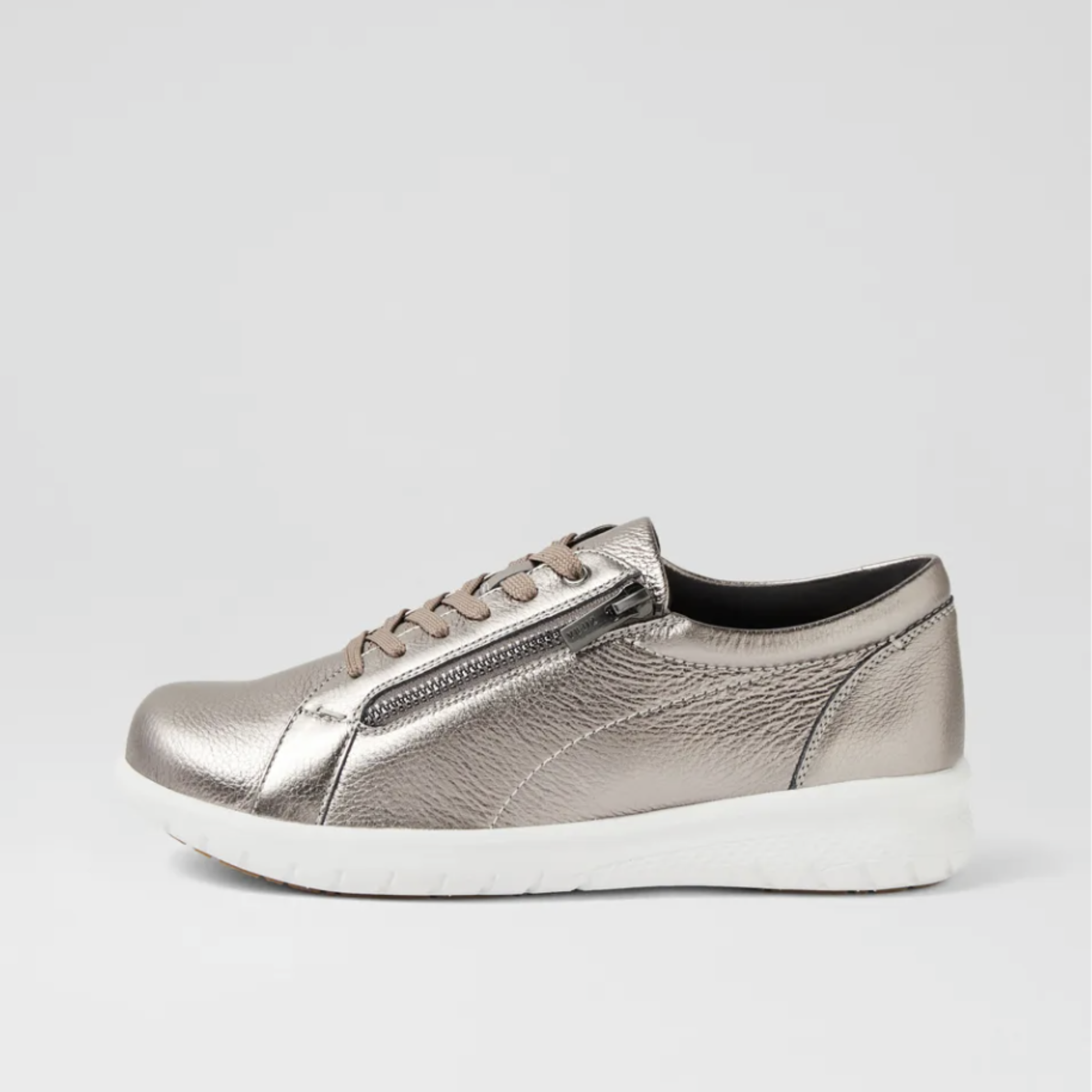 A metallic silver slip-on sneaker with a textured leather-like finish, matching silver laces, a zippered side detail, and a thick white sole, shown against a light gray background.